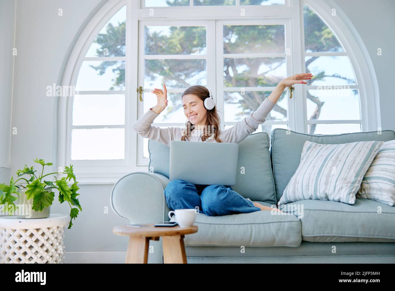 Verlieren Sie sich in Ihrem Lieblingslied. In voller Länge eine attraktive junge Frau, die Musik hört, während sie sich zu Hause auf dem Sofa entspannt. Stockfoto