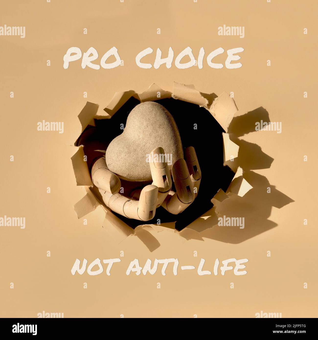 Text Pro Choice, nicht Anti-Life. Karton Herz in Holzmodell Hand durch Papier Loch in Papier. Stockfoto