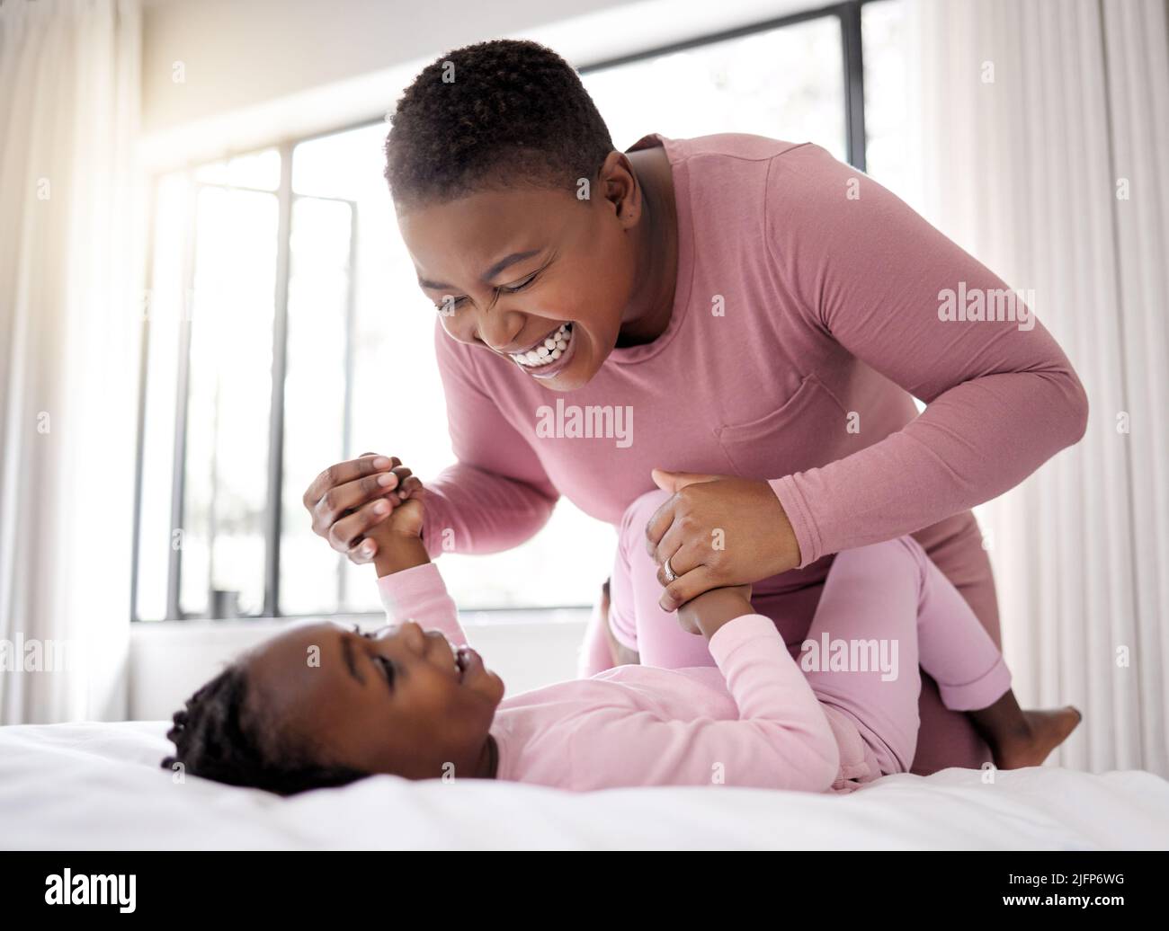 Engel verkörpern sich. Aufnahme einer schönen jungen Frau, die sich zu Hause im Bett mit ihrer Tochter anklebte. Stockfoto