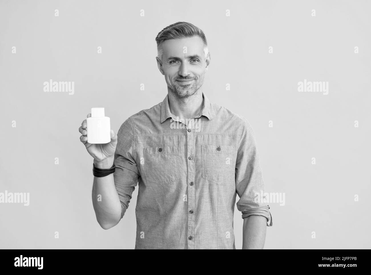 Tägliche Vitamine und Nahrungsergänzungsmittel. Männlich bieten Schmerzmittel. Lächelnder Mann halten Glas mit Medikamenten Pillen Stockfoto