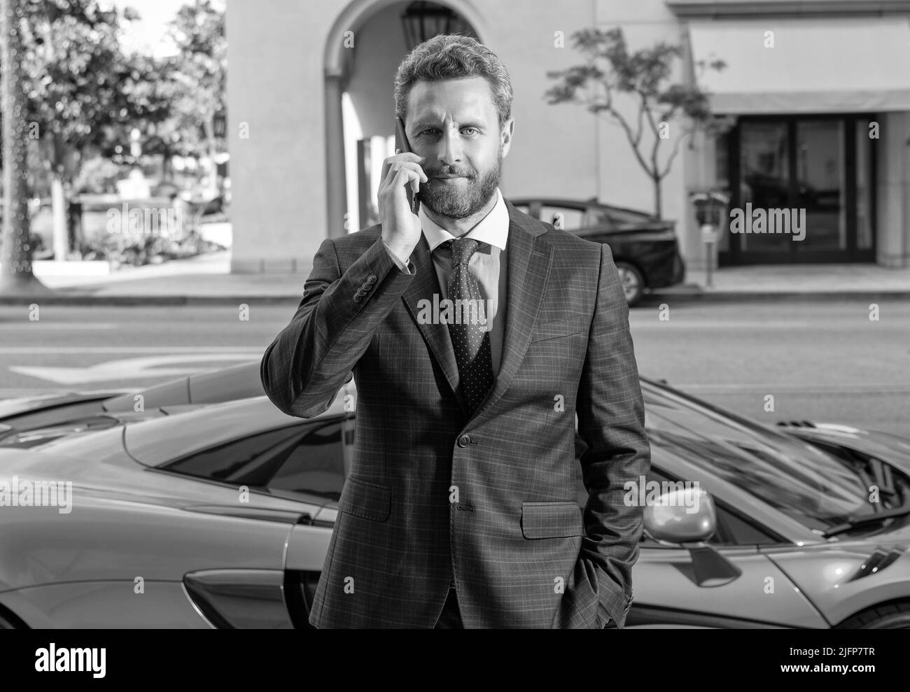 Der Händler spricht auf dem Smartphone neben dem Auto Stockfoto