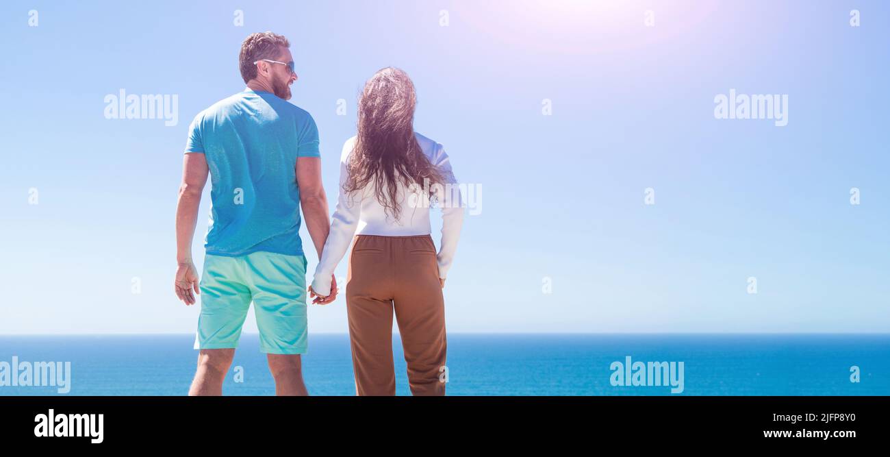 Banner eines verliebten Paares, das sich am Strand umarmt, junge Familie, die weit schaut. Reiseurlaub. Glücklicher Mann und Frau halten die Hände. Ein Paar geht weiter Stockfoto