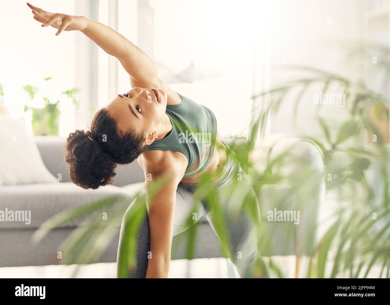 Ich lasse die Zeit nicht durch meine Finger gleiten. Aufnahme einer jungen Frau, die in ihrem Wohnzimmer Yoga praktiziert. Stockfoto