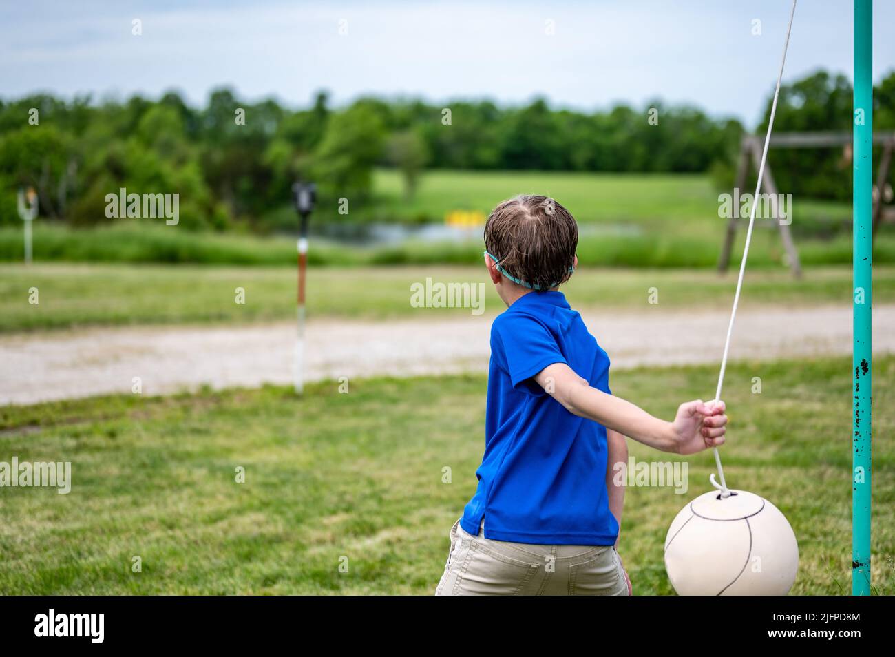 Tetherball wird in einem Spiel mit einem kleinen Jungen getroffen und umgeseilt. Stockfoto