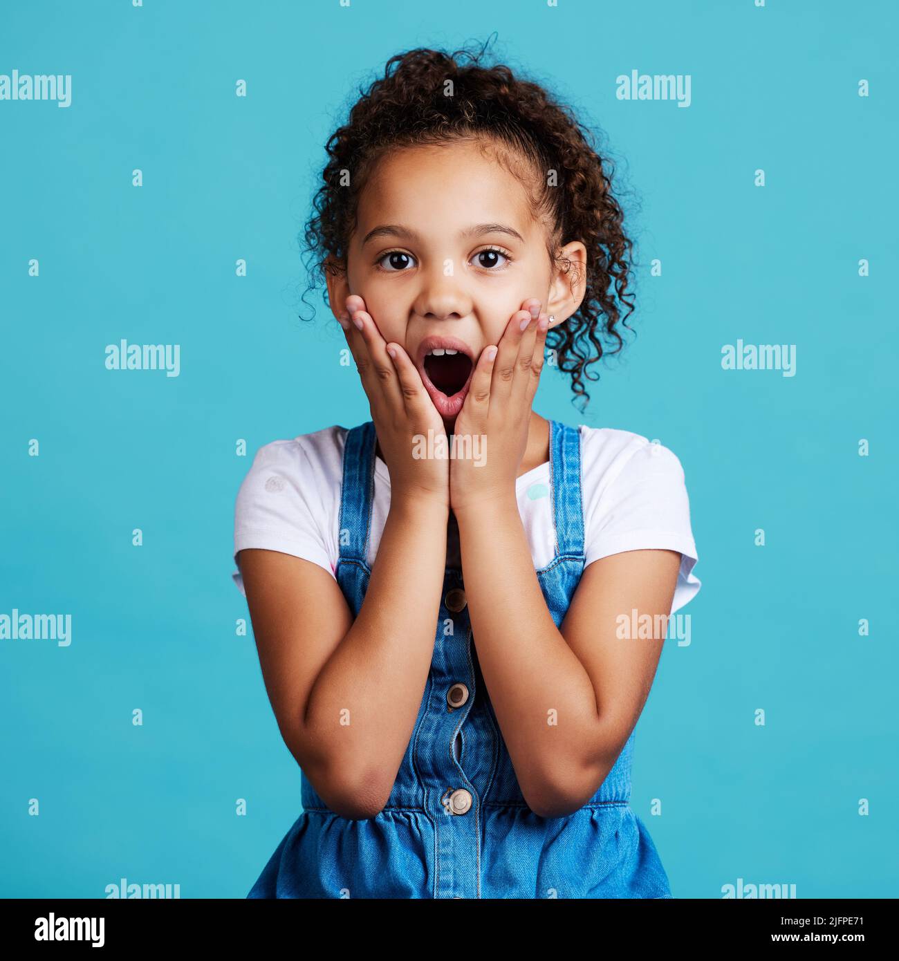 Das habe ich nicht erwartet. Aufnahme eines kleinen Mädchens, das überrascht vor blauem Hintergrund posiert. Stockfoto