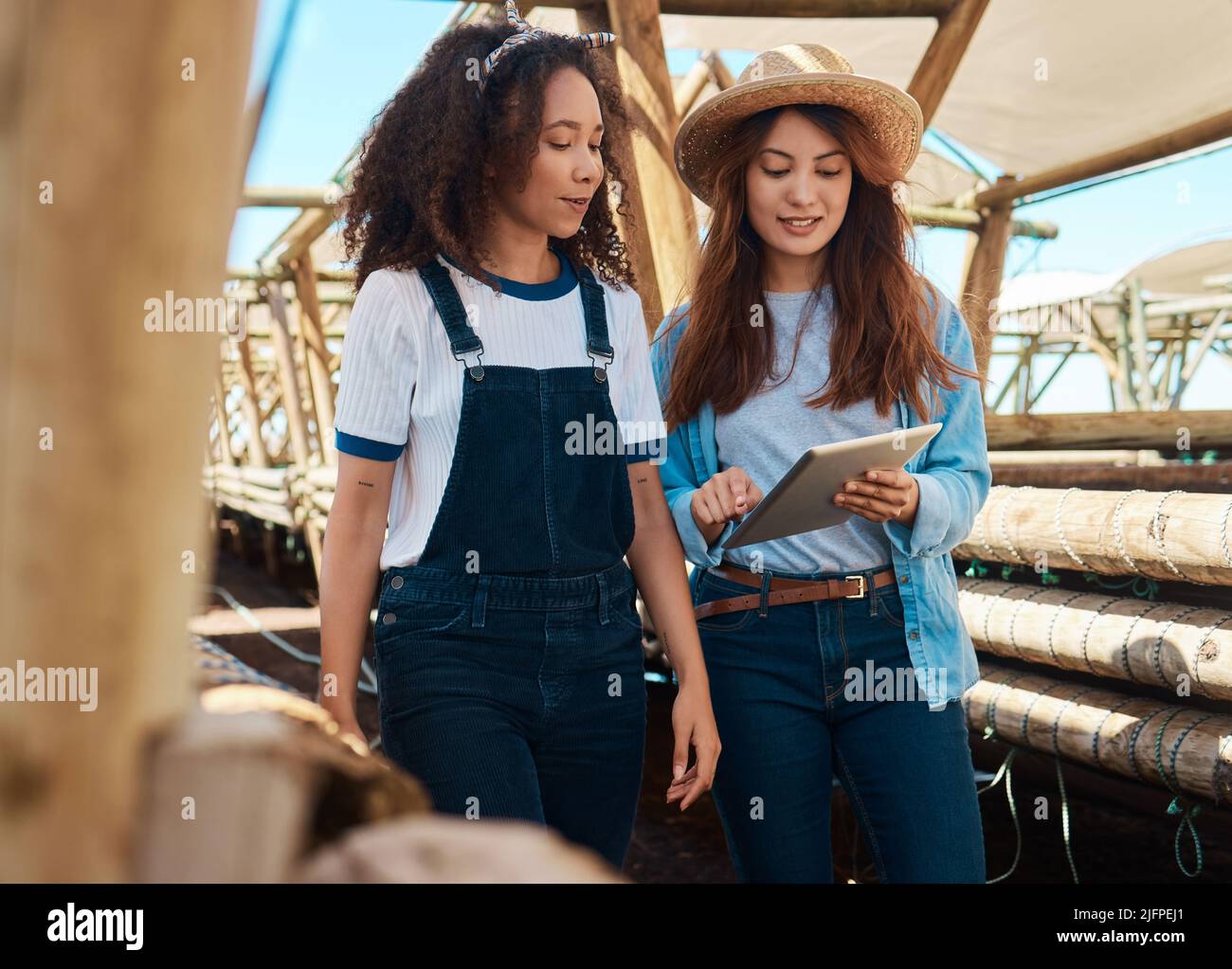 Wenn Sie nicht gut planen, kann es schief gehen. Aufnahme von zwei jungen Frauen, die ein digitales Tablet benutzen, während sie auf einem Bauernhof zusammenarbeiten. Stockfoto