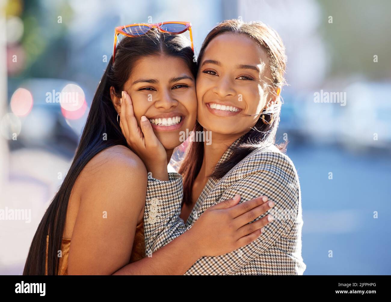 Wiederverbindung in der Stadt. Beschnittenes Porträt von zwei attraktiven jungen Freundinnen, die sich umarmen, während sie in der Stadt unterwegs sind. Stockfoto
