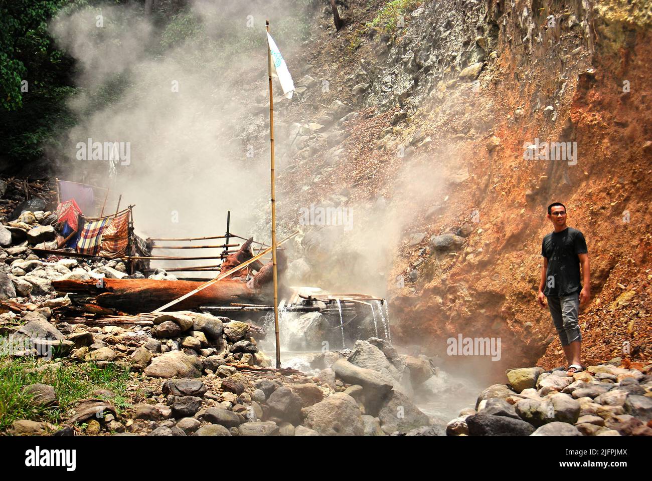 Ein Mann, der vor einer heißen Quelle am Fuße des Vulkans Mount Rajabasa in Way Belerang, Kalianda, South Lampung, Lampung, Indonesien, steht. Stockfoto