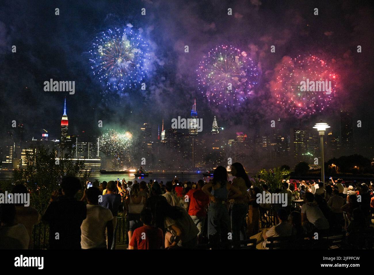 Das Macy's Feuerwerk vom 4. Juli leuchtet vom Greenpoint Landing E aus den Himmel über Midtown Manhattan und dem Empire State Building Stockfoto