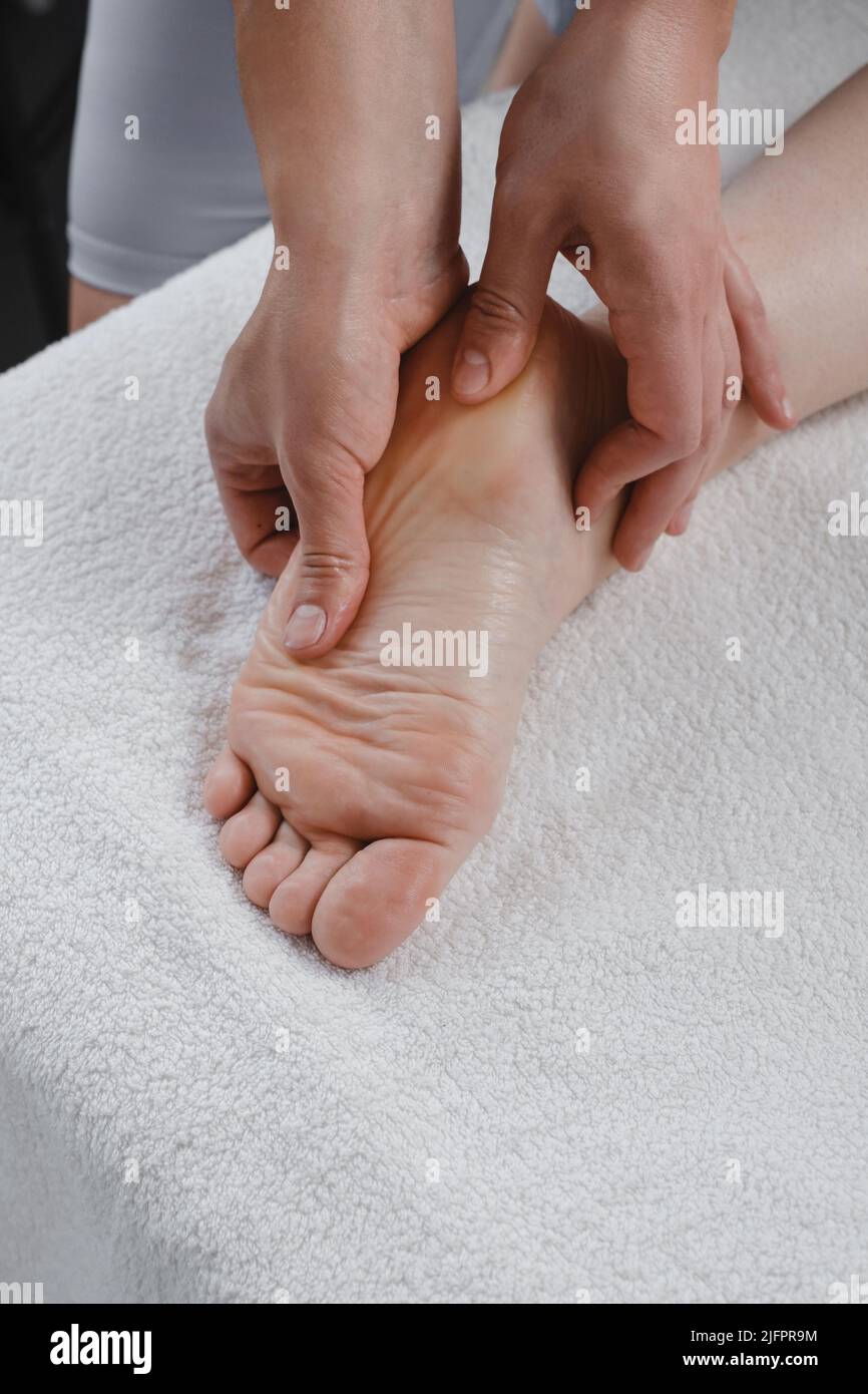 Fußmassage-Behandlung durch professionellen Masseur im Spa-Resort. Wellness, Stressabbau und Verjüngungskonzept. Draufsicht auf weißem Handtuch Stockfoto