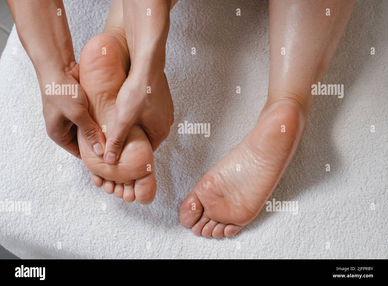 Fußmassage-Behandlung durch professionellen Masseur im Spa-Resort. Wellness, Stressabbau und Verjüngungskonzept. Draufsicht o weißes Handtuch Stockfoto