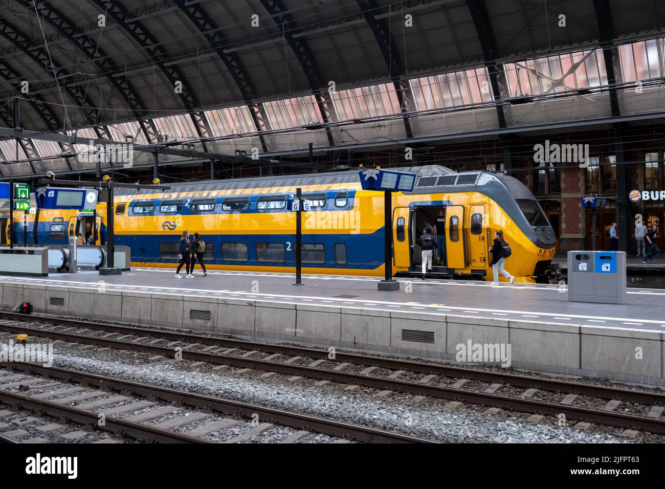 Amsterdam, Niederlande - 21. Juni 2022: Menschen steigen in den Nederlandse Spoorwegen-Zug im Amsterdamer Hauptbahnhof ein Stockfoto