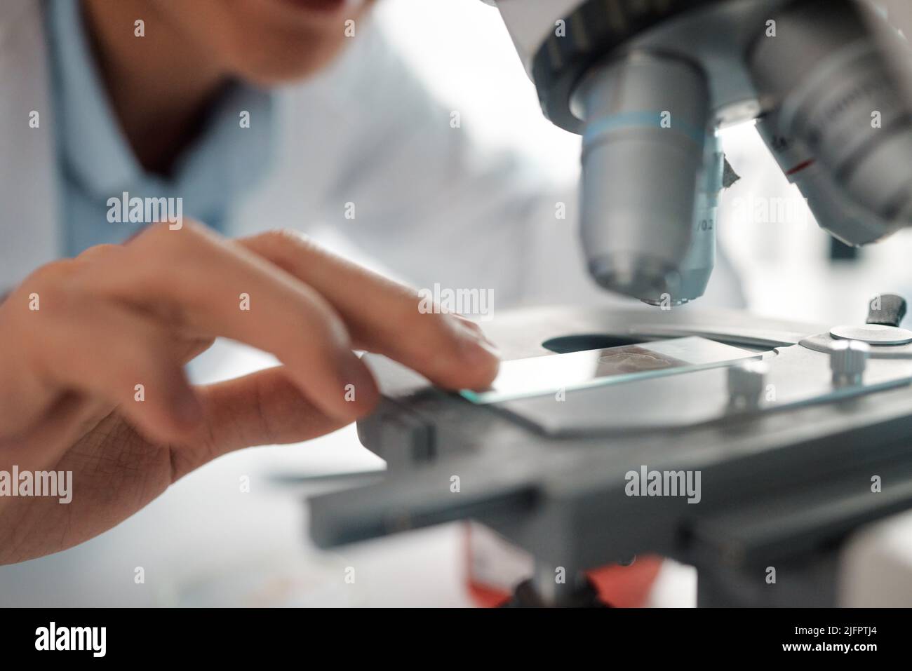 Ich Frage mich, was das bringt. Aufnahme eines männlichen Technikers, der einen Objektträger unter einem Mikroskop positioniert. Stockfoto