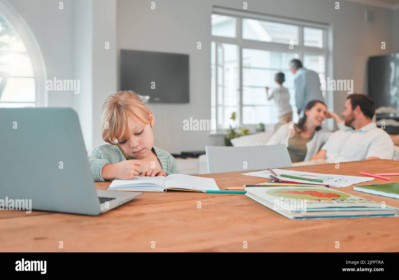 Seriöse junge Mädchen, die in einem Notizbuch schreibt und ihre Hausarbeit macht, während sie zu Hause an einem Tisch in der Lounge sitzt. Kleines kaukasisches Kind konzentrierte sich auf Stockfoto