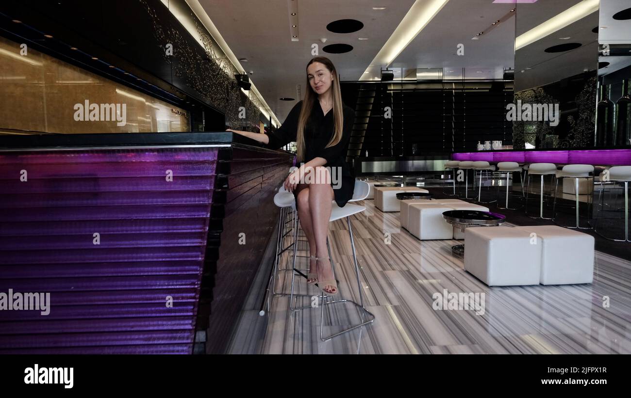 Attraktive, schnaffe Lady mit langen, brünetten Haaren im Lounge Bar Cafe Restaurant Stockfoto