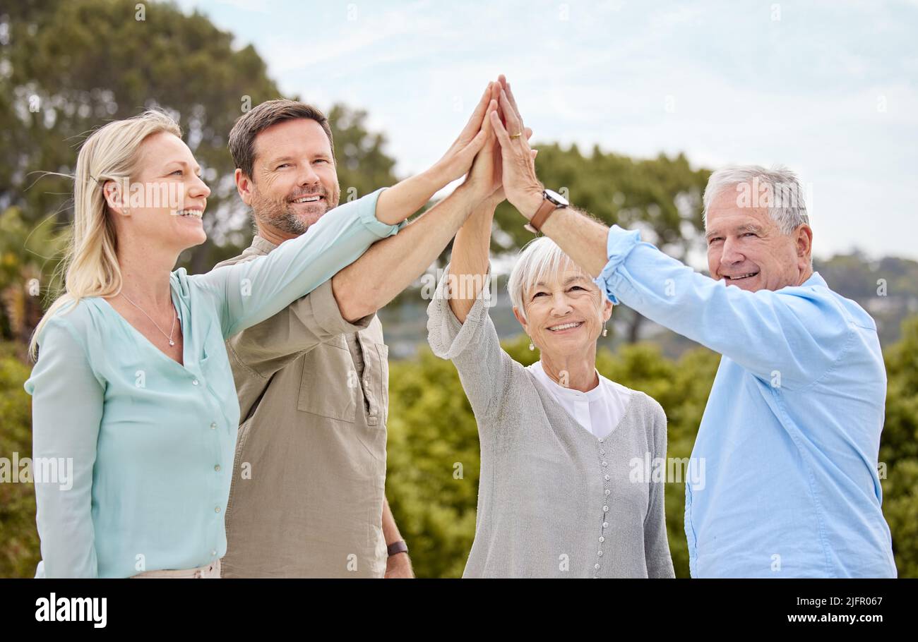 Freuen Sie sich mit Ihrer Familie in dem schönen Land. Aufnahme einer Familie, die sich im Garten zu Hause gegenseitig eine hohe fünf schenkt. Stockfoto