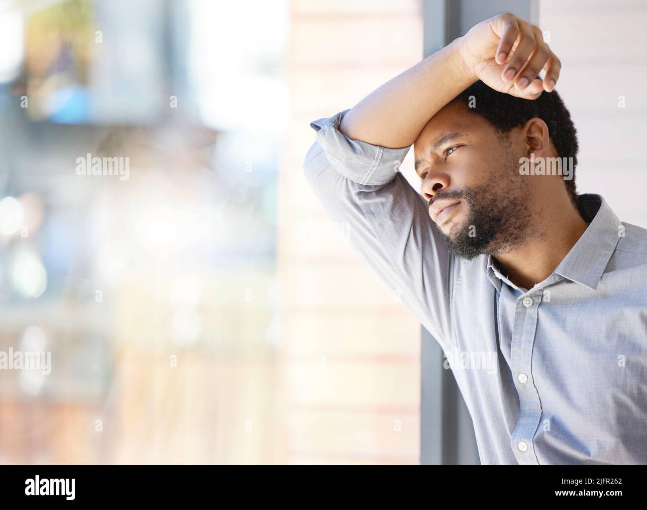 Zu viel zu tun, zu viel zu betonen. Aufnahme eines jungen Geschäftsmannes, der gestresst vor einem Fenster in einem Büro steht. Stockfoto