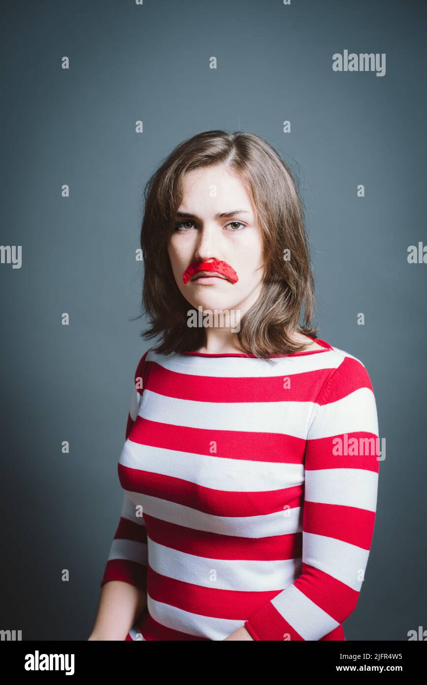 Junge Frau mit Maske vor grauem Hintergrund im Studio. Junge Frau mit Maske vor grauem Hintergrund im Studio. Stockfoto