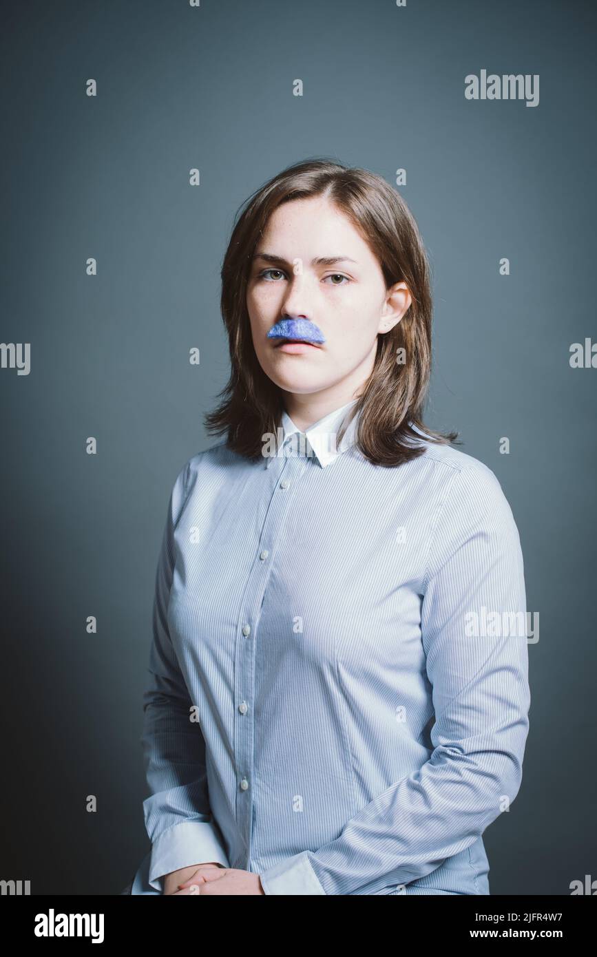 Junge Frau mit Maske vor grauem Hintergrund im Studio. Junge Frau mit Maske vor grauem Hintergrund im Studio. Stockfoto