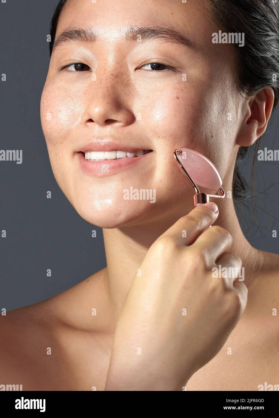 Meine Haut sagt dir, ob es funktioniert oder nicht. Studioaufnahme einer schönen jungen Frau mit einem Gesichtsroller auf ihrer Haut. Stockfoto