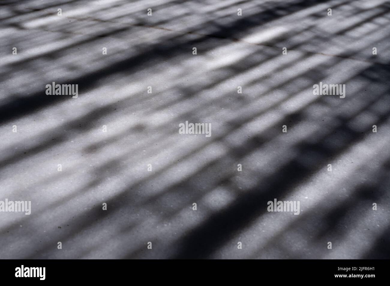Nahaufnahme der Schatten, die auf der weißen Marmoroberfläche eines Tisches reflektiert werden. Diagonale Schattenstreifen. Abstraktes Bild einer strukturierten Oberfläche. Stockfoto