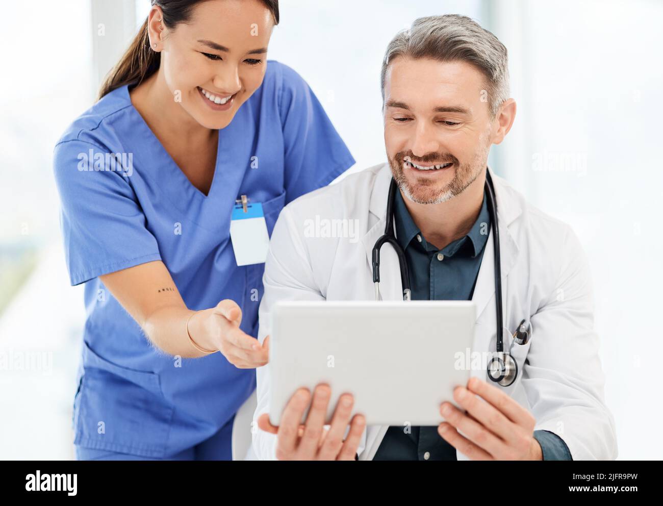 Frühmorgendliche Gespräche mit den Ärzten. Aufnahme von zwei Ärzten, die in einem Büro eine Tablette benutzen. Stockfoto