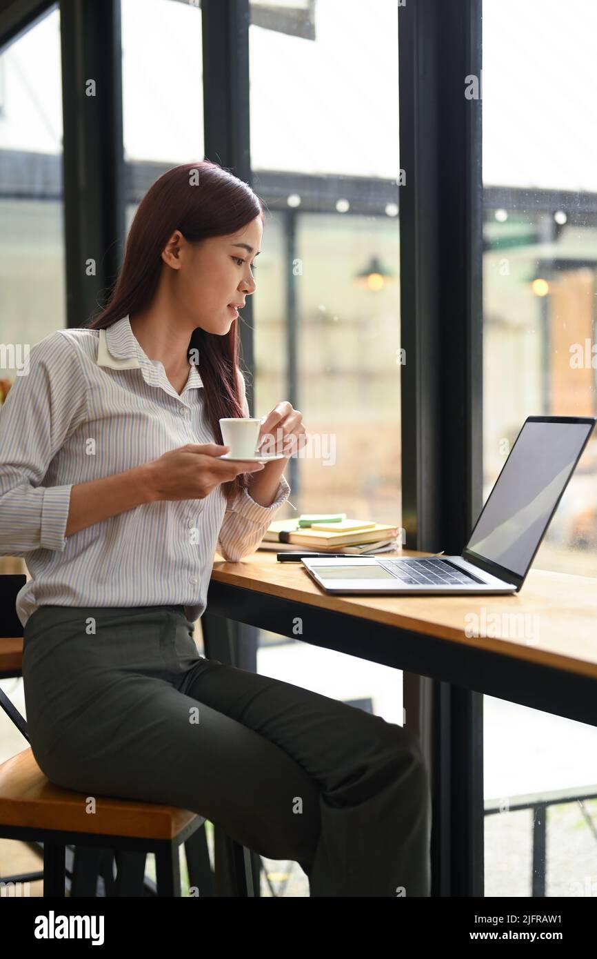 Portrait Unternehmerin trinkt heißen Kaffee und liest E-Mail auf Laptop-Computer Stockfoto