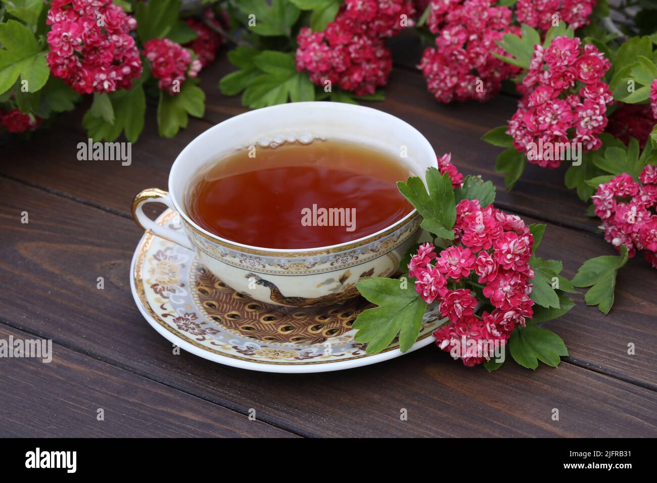 tasse Tee auf braunem Holzhintergrund mit rosa Blüten Stockfoto