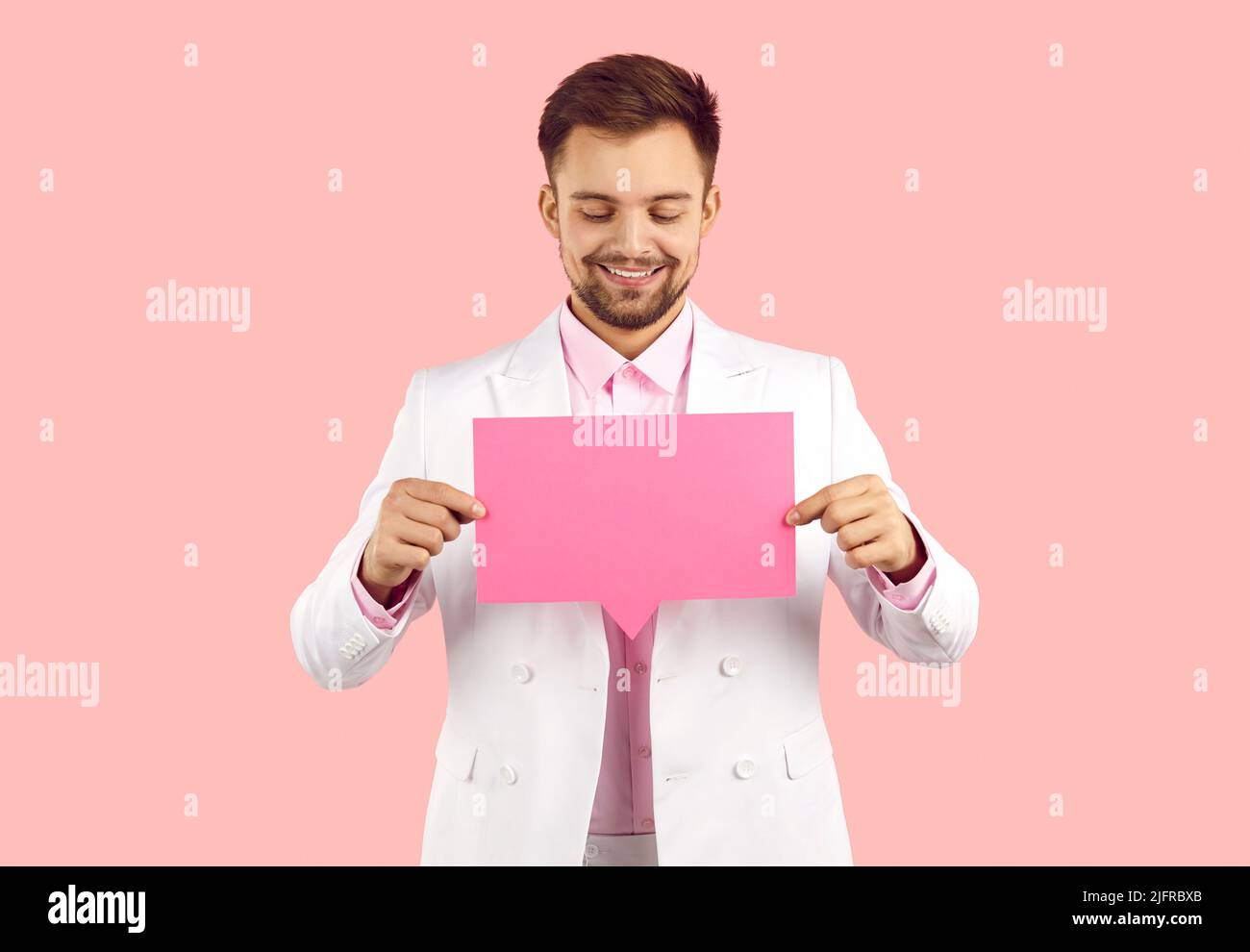 Studio-Porträt eines glücklichen jungen Mannes mit leerer rosa Mockup-Chat-Nachrichtenblase Stockfoto