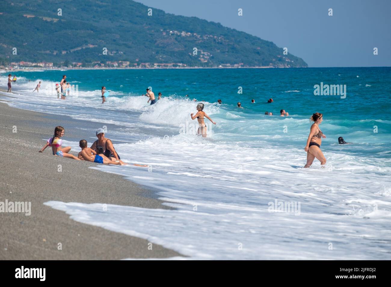 Leute, die Spaß mit den Wellen am Strand haben Stockfoto