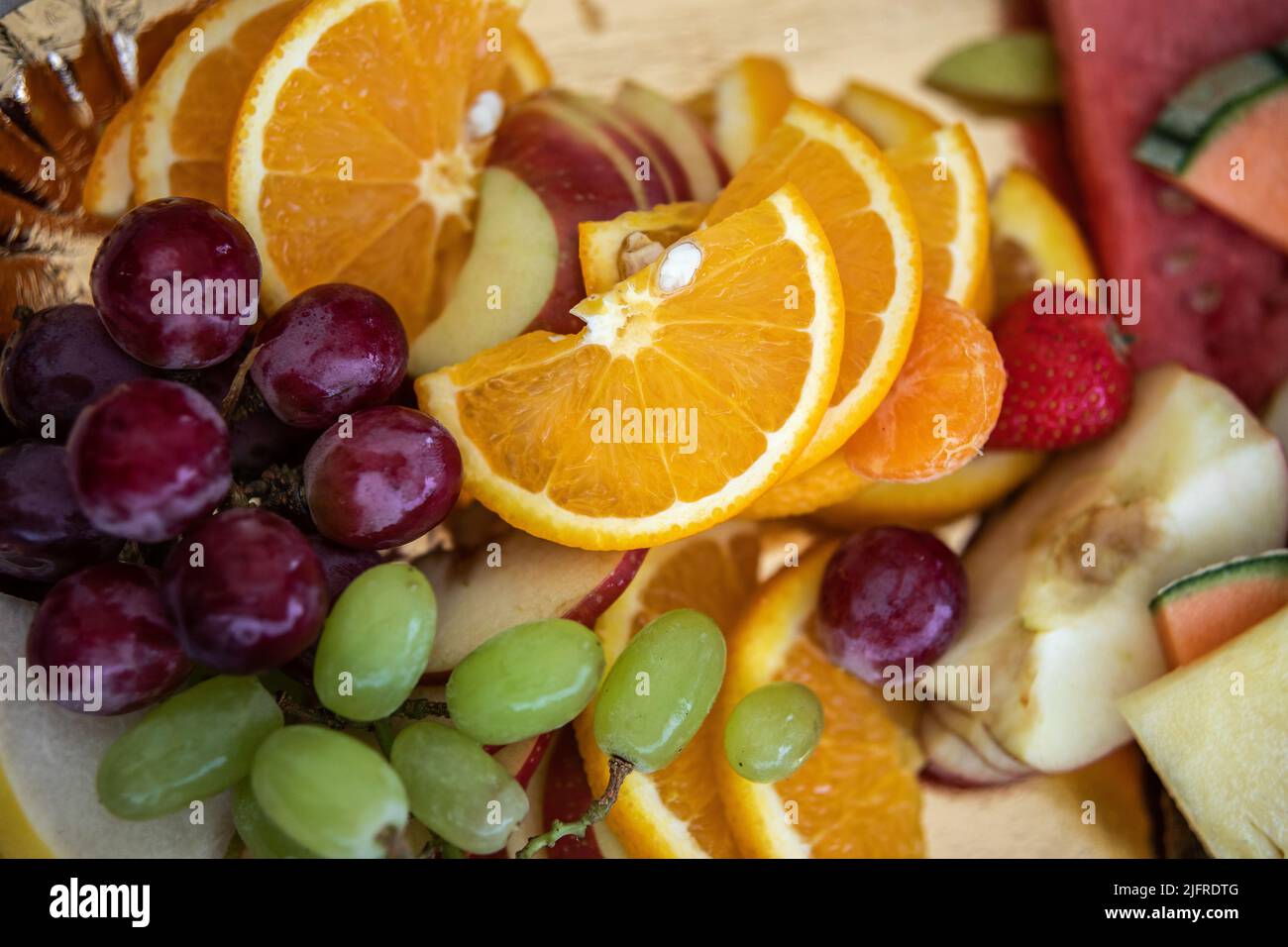 Vielfalt an bunten Früchten. Rote und grüne Weintraube mit Orange. Saftige und essbare Mischung aus geschnittenem Essen. Stockfoto