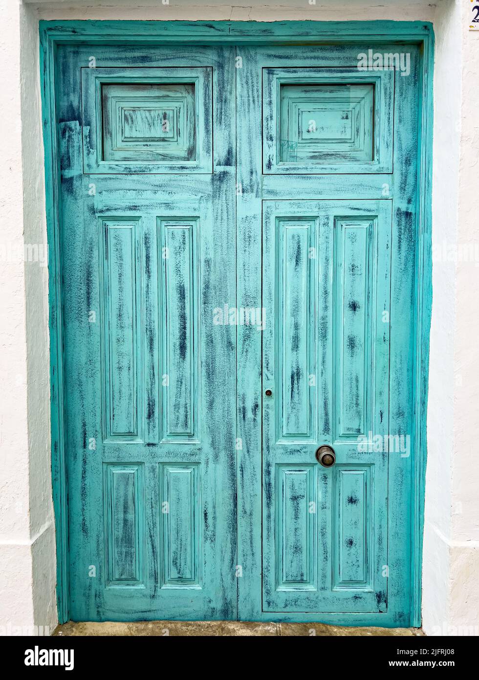 Eine vertikale Aufnahme einer alten türkisfarbenen hohen Tür in einem Eingang Stockfoto