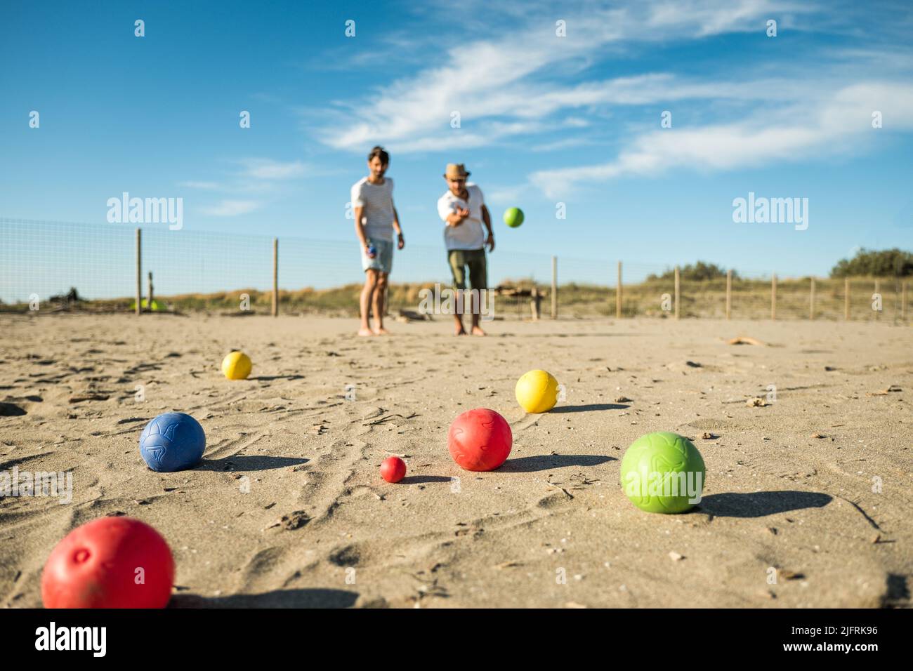 Touristen spielen ein aktives Spiel, Petanque auf einem Sandstrand am Meer - Gruppe von jungen Menschen spielen Boule im Freien in Strandurlaub Stockfoto