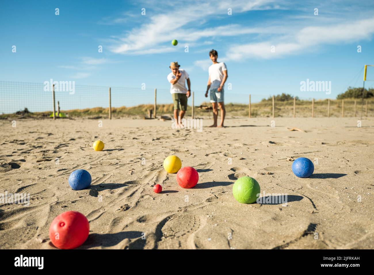 Touristen spielen ein aktives Spiel, Petanque auf einem Sandstrand am Meer - Gruppe von jungen Menschen spielen Boule im Freien in Strandurlaub Stockfoto