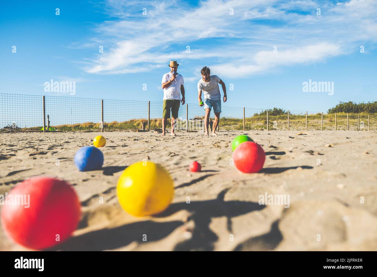 Touristen spielen ein aktives Spiel, Petanque auf einem Sandstrand am Meer - Gruppe von jungen Menschen spielen Boule im Freien in Strandurlaub Stockfoto