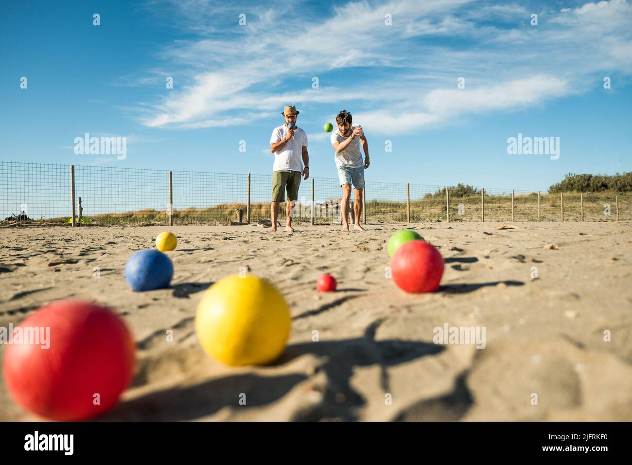 Touristen spielen ein aktives Spiel, Petanque auf einem Sandstrand am Meer - Gruppe von jungen Menschen spielen Boule im Freien in Strandurlaub Stockfoto