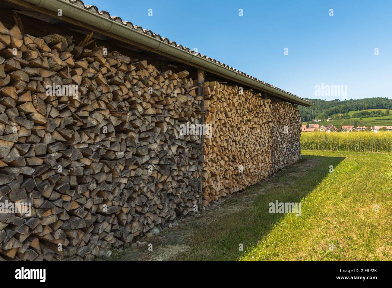 Holzstapel, gestapeltes und geschnittenes Brennholz, in einem offenen Schuppen gelagert Stockfoto