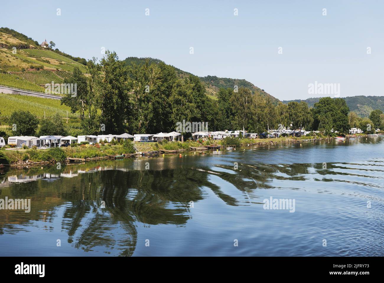 Camping, wildes Campen in Zelten und Wohnwagen am Rheinufer in Deutschland. Zelte spiegeln sich im Wasser. Stockfoto