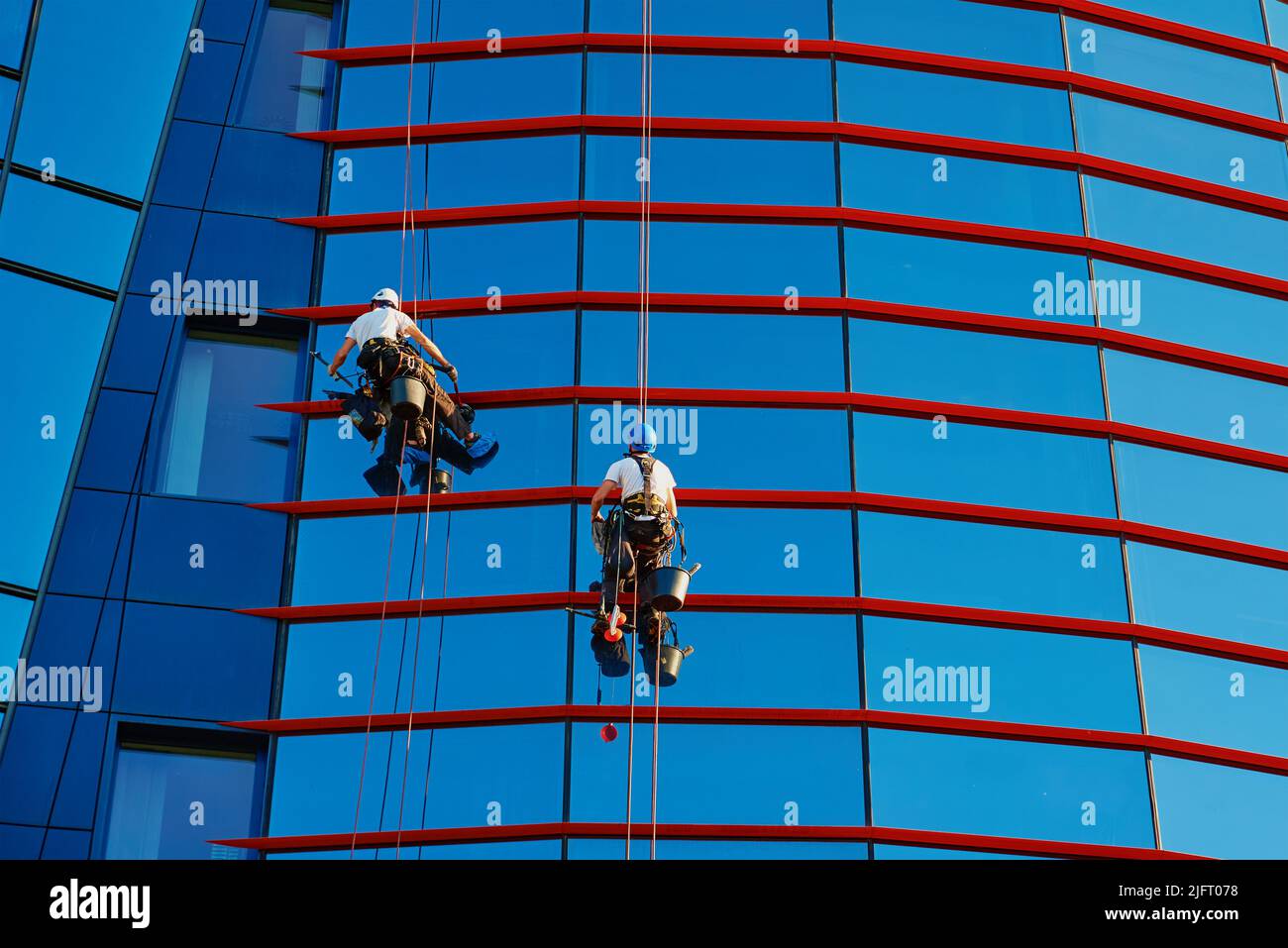 Zwei Arbeiter putzen Fenster im Business Center, Industrielle Alpinisten waschen außen des Wolkenkratzers, gefährliche riskante Arbeit in der Höhe, Reinigungsservice Stockfoto