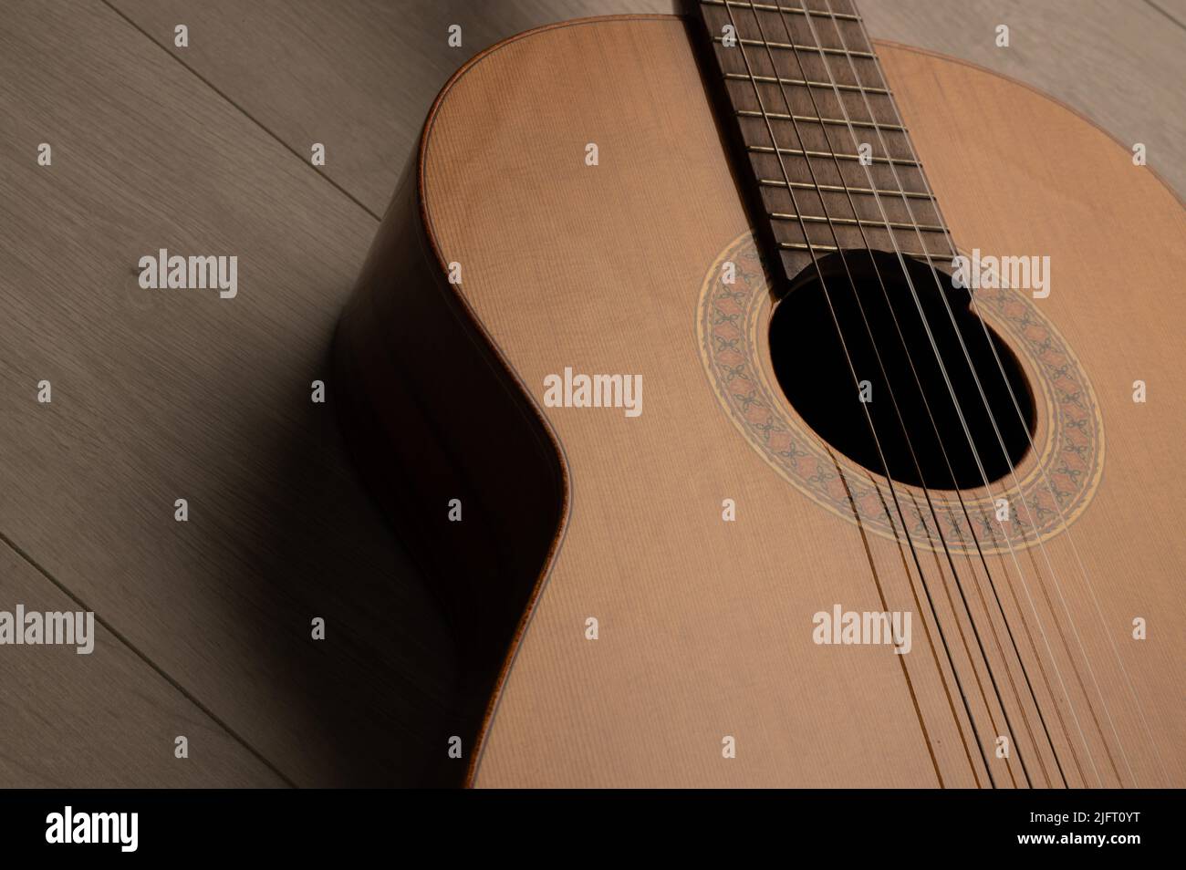 Klassischer Gitarrenkörper aus nächster Nähe, auf einem hellen Holzhintergrund mit Kopierraum Stockfoto