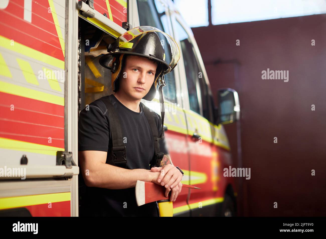 Foto von Feuerwehrmann mit Helm und Axt gegen Feuerwehrmann. Stockfoto