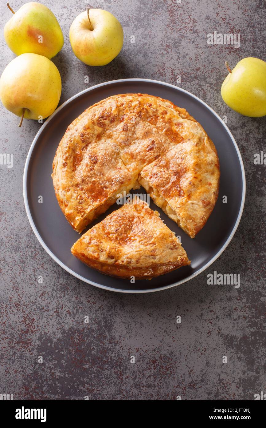 Apfelkuchen mit Cheddar-Käse in der Nähe auf dem Teller auf dem Tisch. Vertikale Draufsicht von oben Stockfoto
