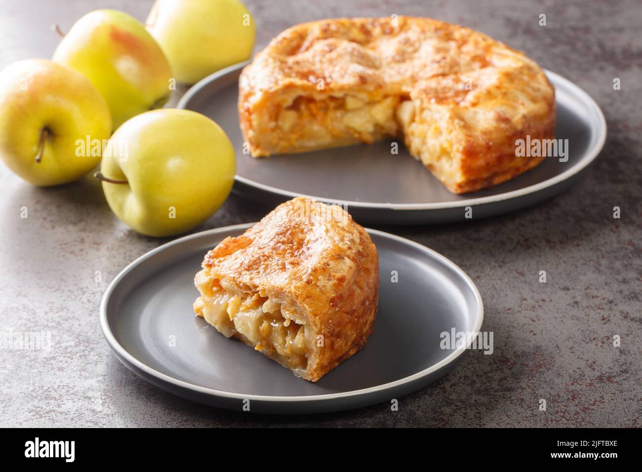 Apfelkuchen mit Käsekruste in der Platte auf dem Tisch zu verschliessen. Horizontal Stockfoto