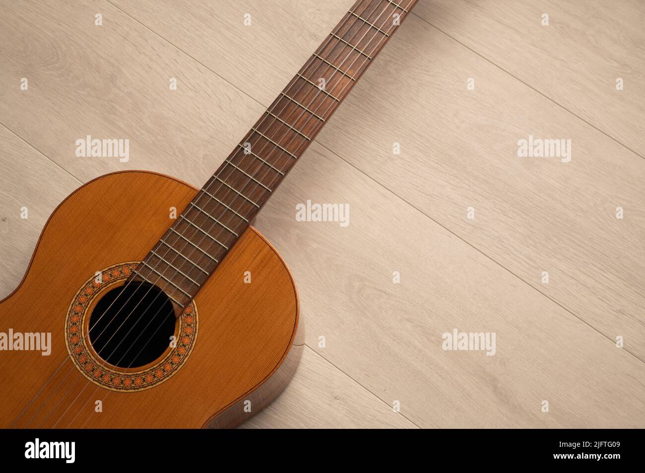 Klassischer Gitarrenkörper aus nächster Nähe, auf einem hellen Holzhintergrund mit Kopierraum. Stockfoto