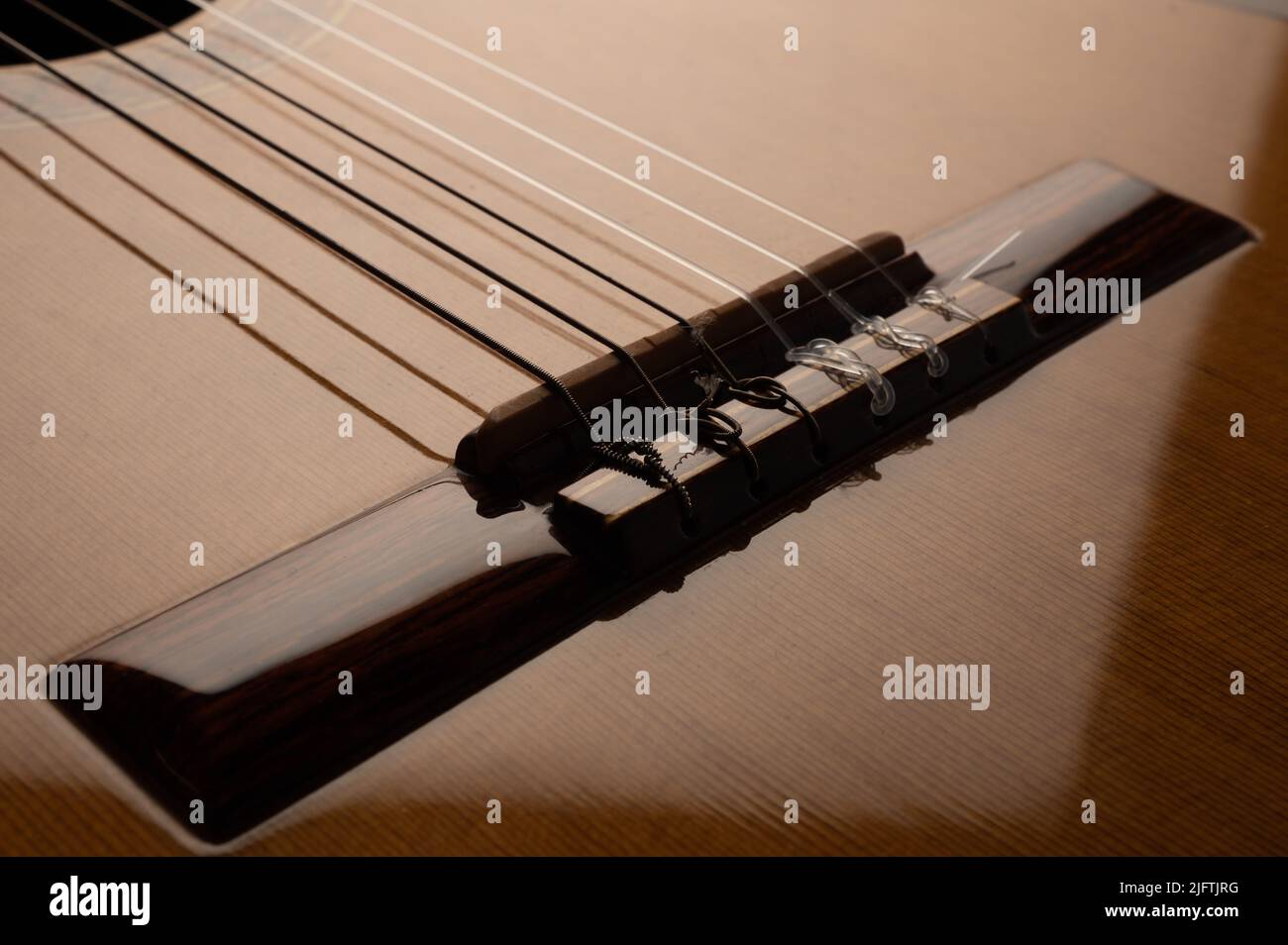Spanische klassische 6-saitige Gitarrenbrücke und Sattel aus nächster Nähe mit einer reflektierten Vignette Stockfoto