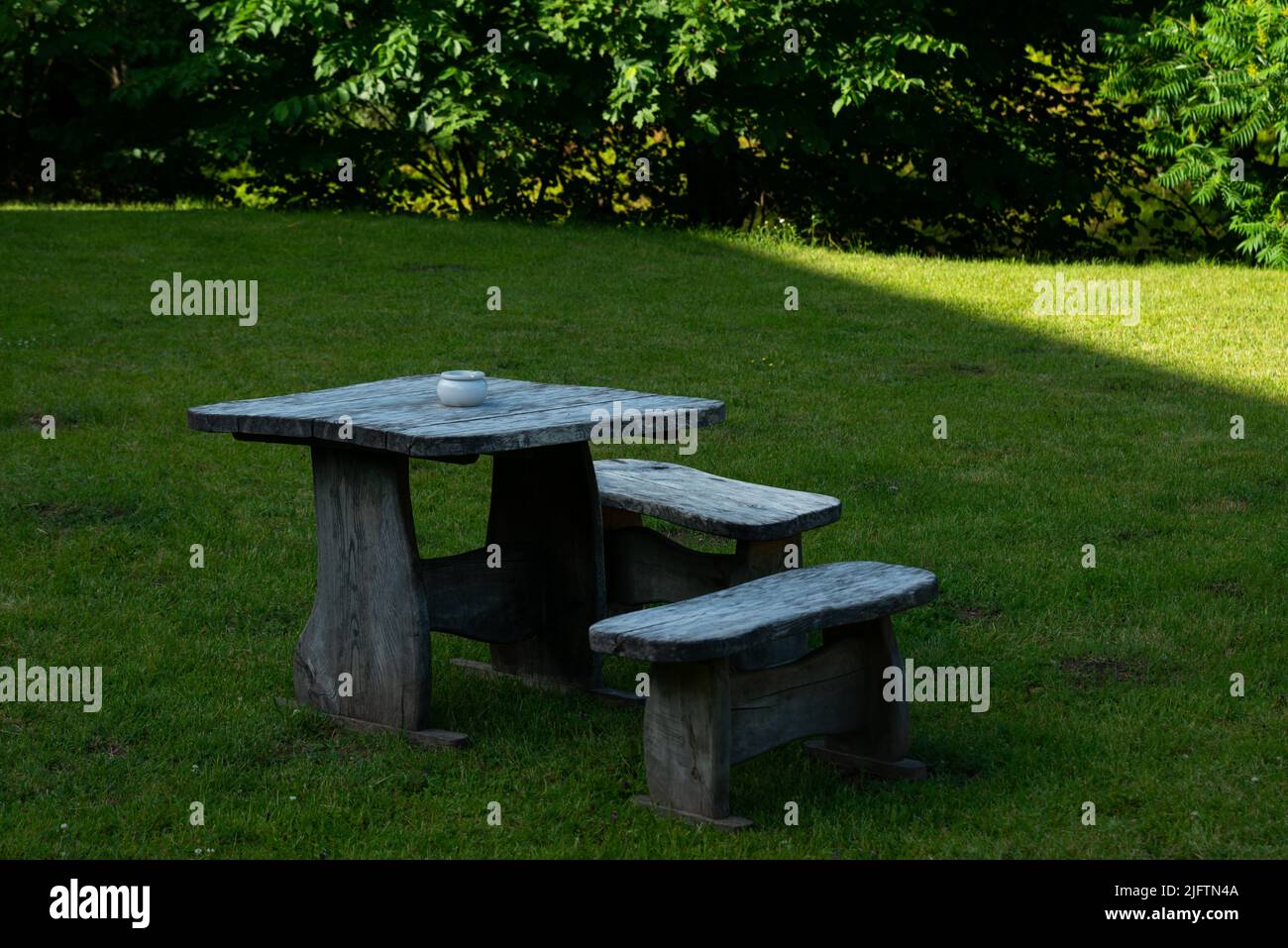 Holztisch mit Bänken und einem Aschenbecher auf einem Rastplatz auf grünem Gras. Stockfoto