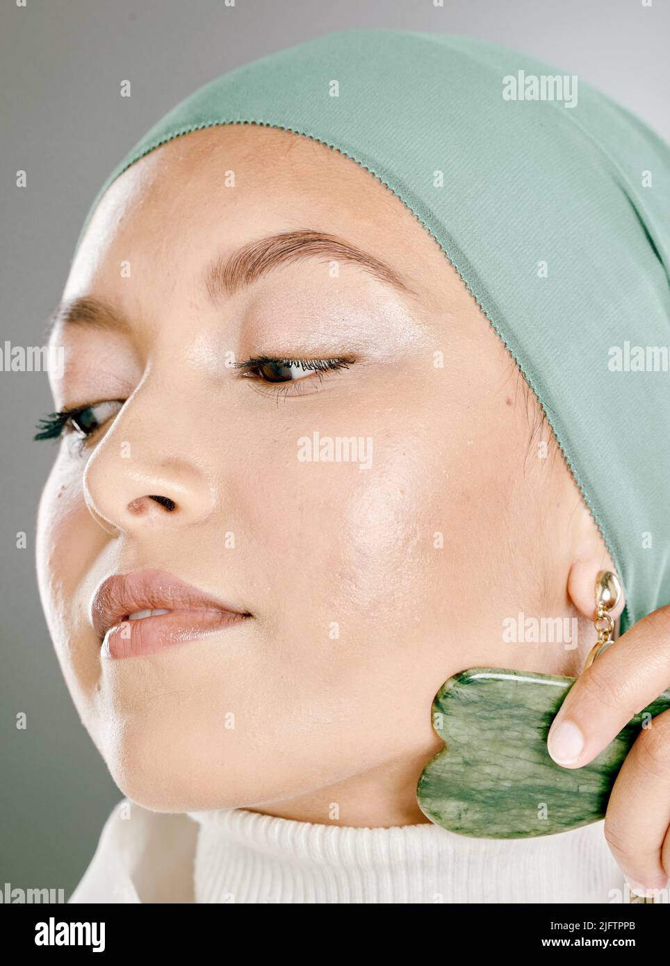 Frau mit einem Gesichtsstein auf ihrem Gesicht. Beauty-Model macht ihre morgendliche Hautpflege-Routine mit einem Jadestein. Junge Frau mit einem Gua Sha Produkt für Stockfoto