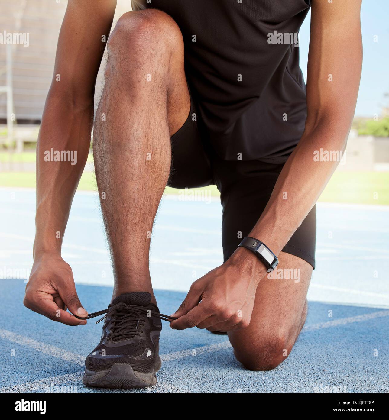 Sportler, der sich auf ein Rennen auf der Strecke vorbereitet. Nahaufnahme eines Sportlers, der seine Turnschuhe befestigt, um ein Stolpern zu verhindern, während er sich für das Ausdauertraining vorbereitet Stockfoto