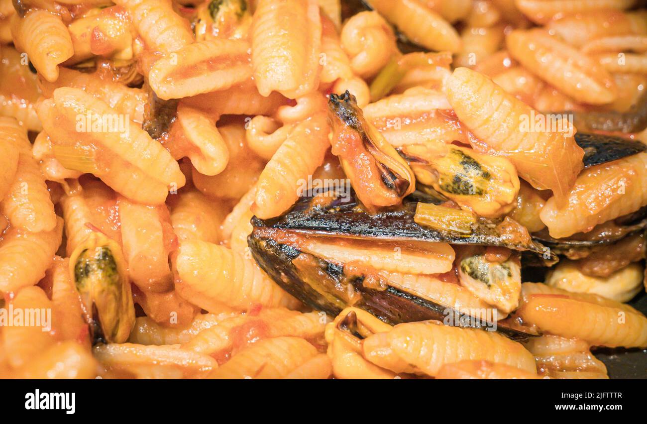 Nahaufnahme eines typisch italienischen Gerichts. Sardische Gnocchi mit schwarzen Muscheln mit Tomaten, Zwiebeln, Knoblauch und Pfeffer. Stockfoto