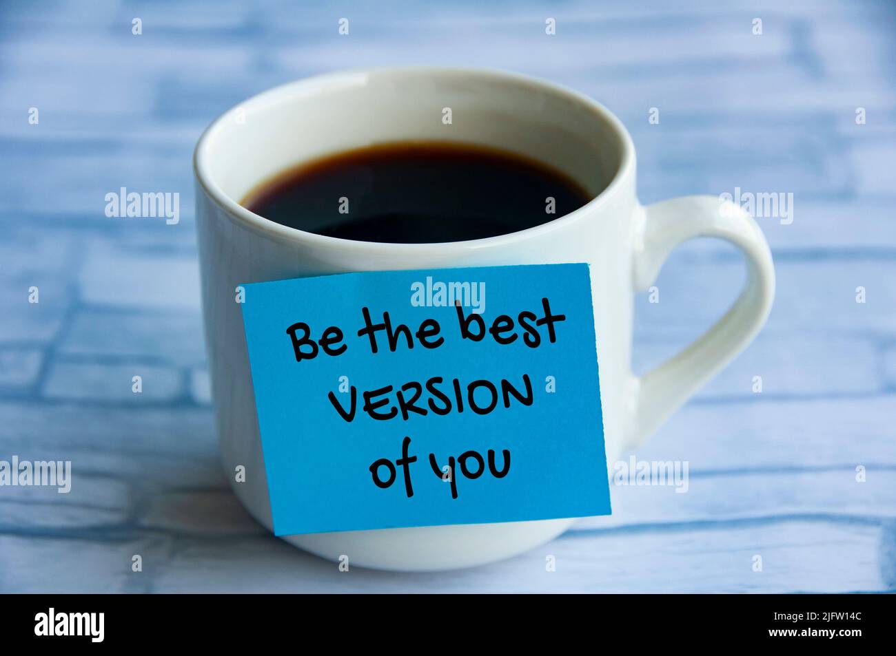 Seien Sie die beste Version von Ihrem Text auf blauem Notizblock, der auf der Kaffeetasse klebt. Motivationskonzept für das Leben Stockfoto